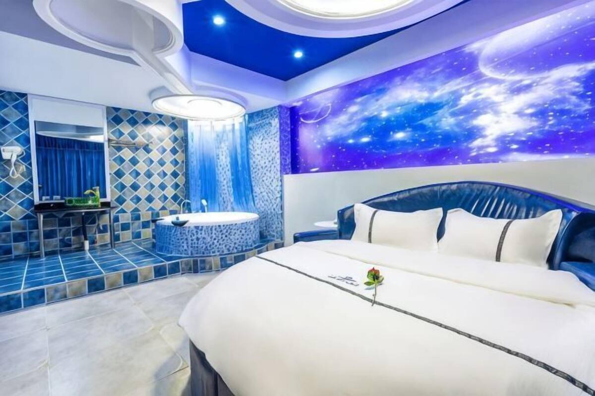 A bedroom with a bed, a vanity, and a wall with a space-themed mural.