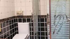 A bathroom with a toilet, a shower area, and a glass door with a palm tree design. - Haihao Business Hotel (Chongqing)