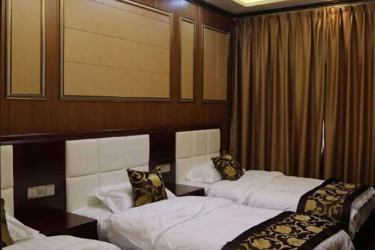 A hotel room with two beds, a wooden headboard, and a large window with curtains.