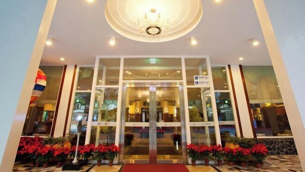 A hotel entrance with a glass door, a chandelier, and potted plants. - Lakeside Resort (Nantou)