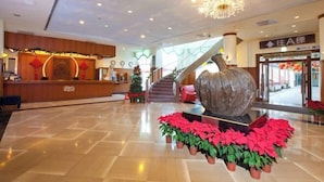 A lobby with a reception desk, a staircase, and a large decorative sculpture. - Lakeside Resort (Nantou)