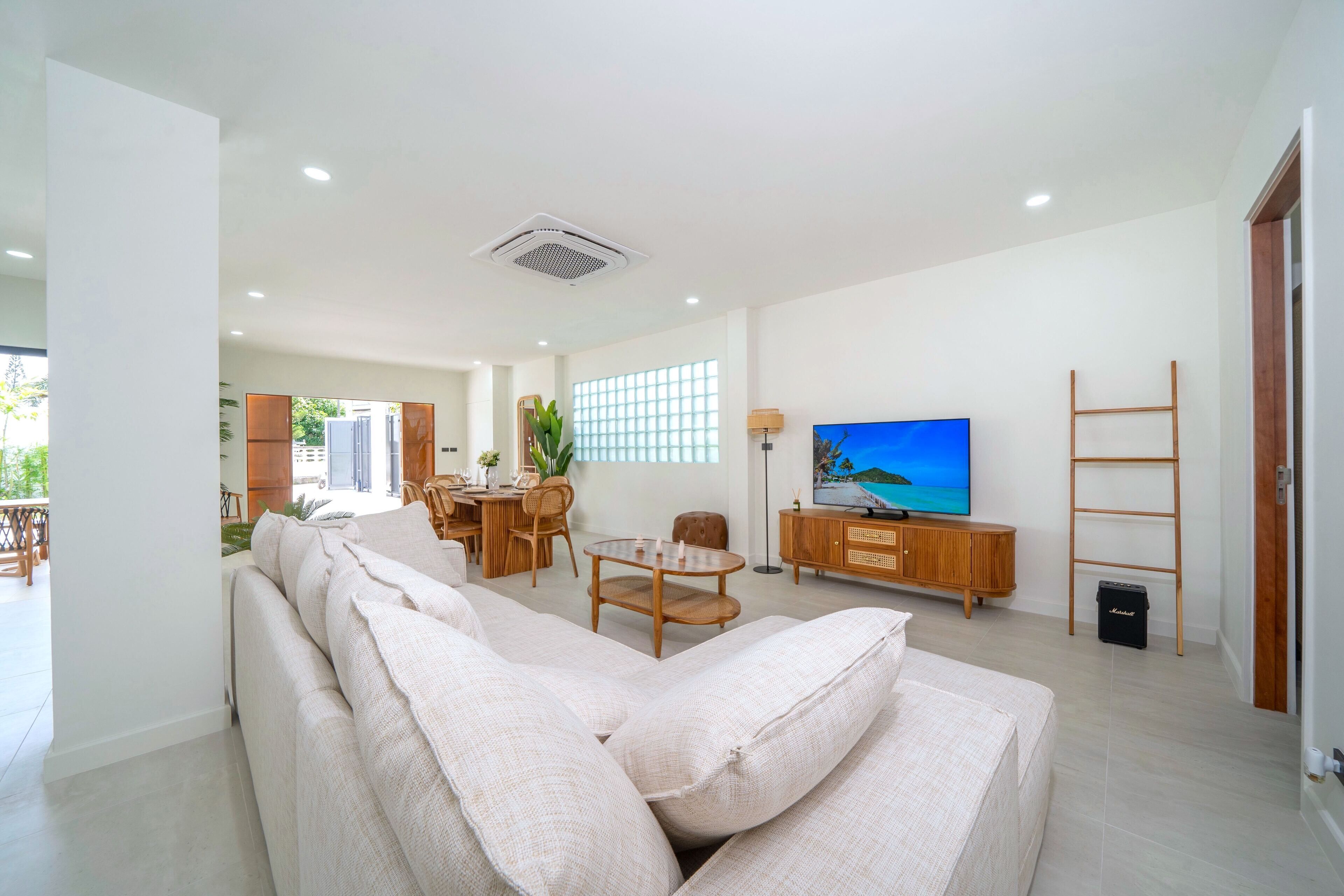 A modern living room with a sofa, TV, wooden furniture, and a balcony view.