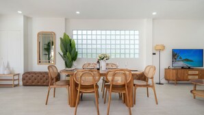 Un salon moderne avec un coin repas, comprenant une grande fenêtre, un téléviseur et un canapé.