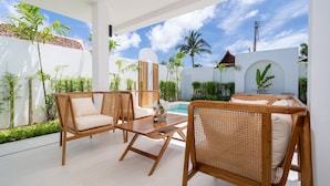 Une terrasse extérieure moderne, dotée de meubles en osier et d’une piscine.