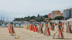 Une plage de sable avec des parasols et des chaises longues aux couleurs vives.