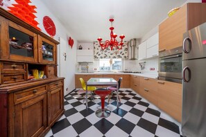 Une cuisine avec un carrelage à motifs, des meubles en bois, un réfrigérateur en acier inoxydable et un lustre rouge.