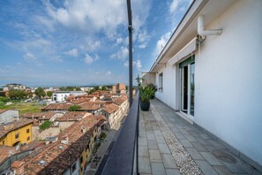 Un balcon donnant sur une vue de la ville, une plante en pot et un ciel dégagé.