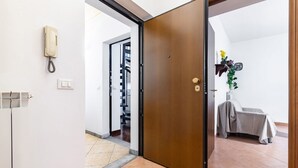 Hotellihuone, jossa on puinen ovi, puhelin, patteri ja päällisen peittämä tuoli.