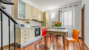 A modern kitchen with wooden cabinets, a microwave, and a dining area with a table and chairs. - GuestHost - Cozy apartment of 80 sqm, on two levels, for 2 people, located on the 1st floor of a building with lift (steps to access: not suitable for disabled people).The property is located in the heart of the historic center of Palermo (Restricted Tra (Palermo)