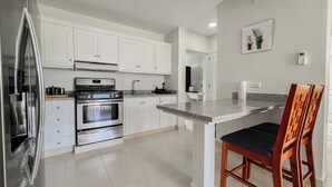 A modern kitchen with white cabinets, stainless steel appliances, and a granite countertop. - Goistay Punta Cana Sol, Playa Pool 15 Min Airport (Punta Cana)