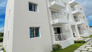 A modern white building with multiple balconies and a paved walkway. - Goistay Punta Cana Sol, Playa Pool 15 Min Airport (Punta Cana)