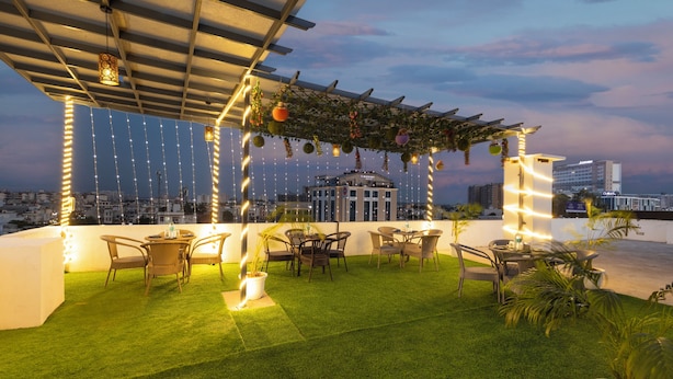 Un espace extérieur aménagé avec des tables et des chaises, des guirlandes lumineuses et une vue sur le paysage urbain.