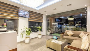 Un hall d’hôtel moderne doté d’un grand téléviseur, de sièges confortables, de plantes en pot et d’une entrée en verre.