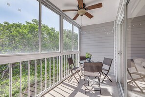 A covered balcony with a ceiling fan, wicker furniture, and a table with a vase. - Holmes Beach Condo Near Anna Maria: Pool Access! (Holmes Beach)