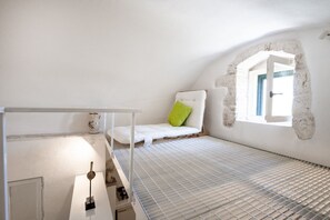 A room with a bunk bed, a small window with a view, and a stone archway.
