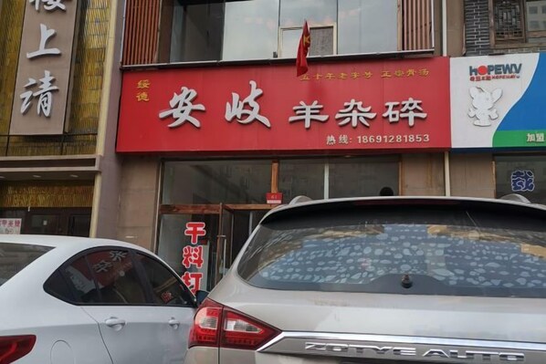 A storefront with a red sign and a car parked in front. - Shiji Jiamei Hotel (Suide)