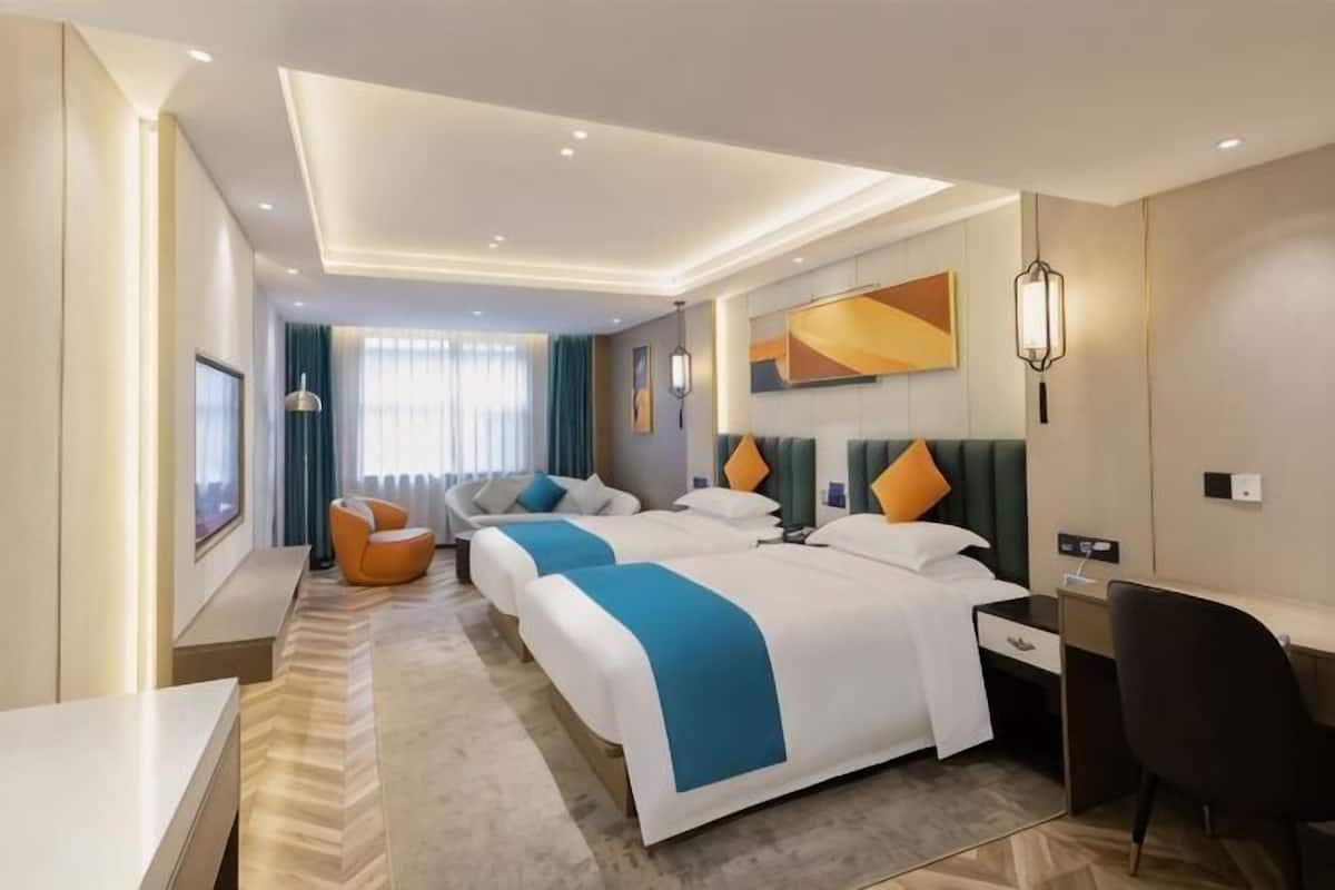 Habitación de hotel con una cama grande, un escritorio, una silla y vistas a la ciudad.