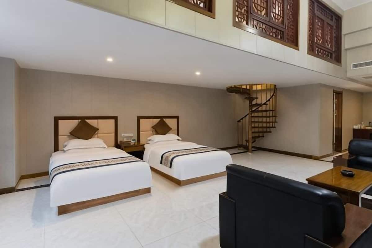 Habitación de hotel con dos camas, una escalera, un escritorio y una silla.