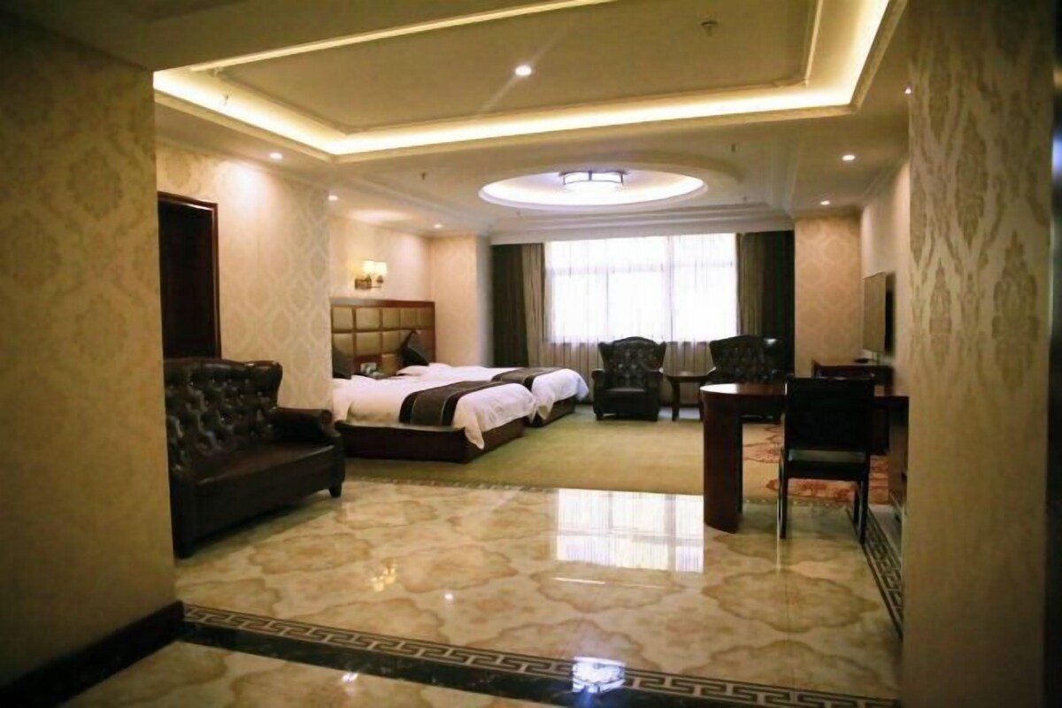 Una habitación de hotel con cama, sofá, escritorio y televisión.
