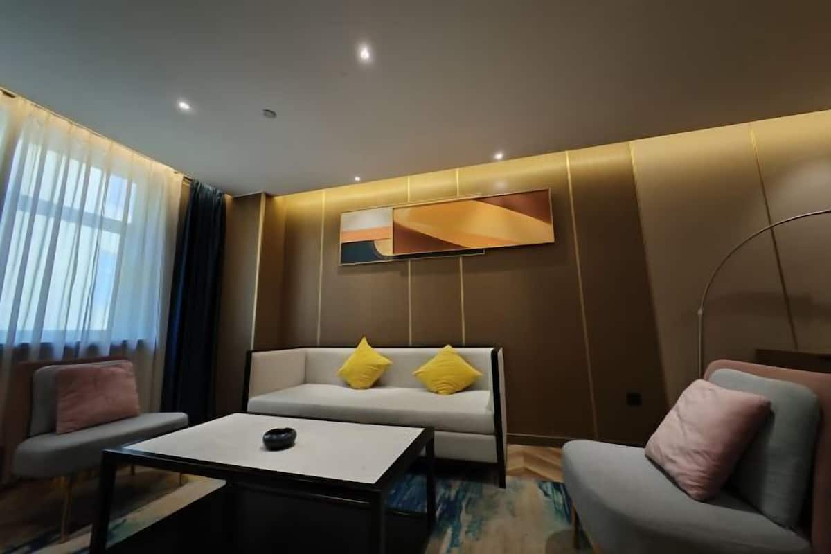 Una sala de estar moderna con un sofá, dos sillones, una mesita de centro y un cuadro en la pared.