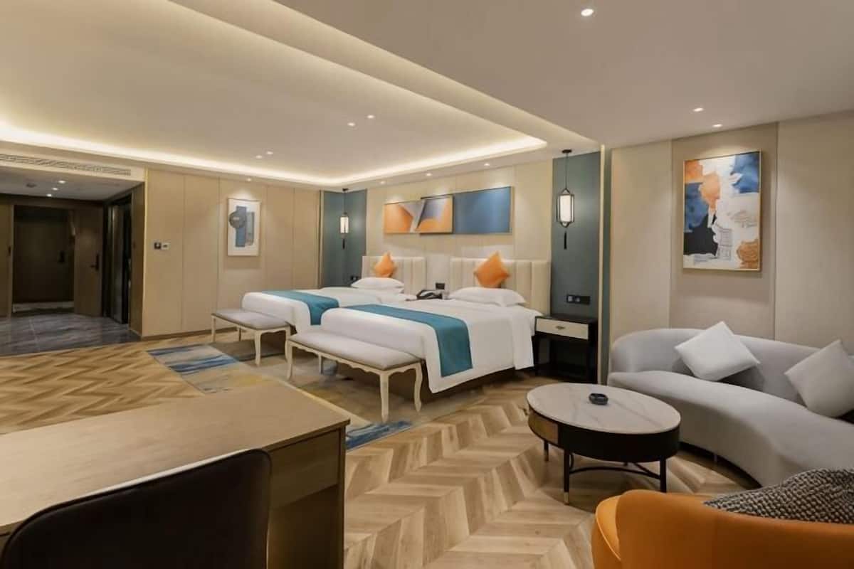 Una habitación de hotel con dos camas, un sofá, una mesita y un escritorio.