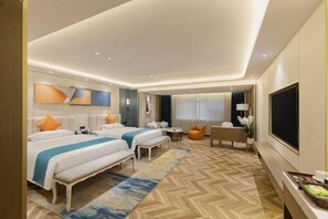 A hotel room with two beds, a TV, a desk, and a seating area.