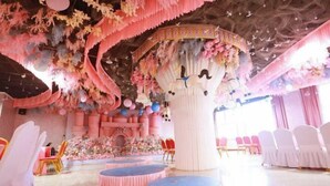 A room with a stage, chairs, and a column with a floral design. - Shiji Jiamei Hotel (Suide)