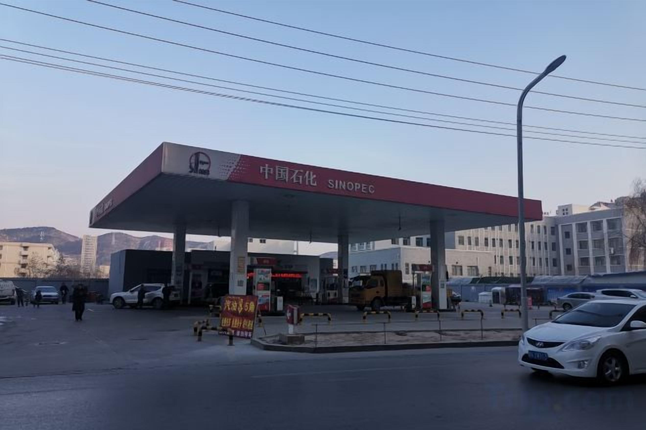 A gas station with a red canopy, multiple fuel pumps, and a clear sky.