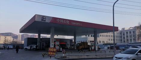 A gas station with a red canopy, multiple fuel pumps, and a clear sky.
