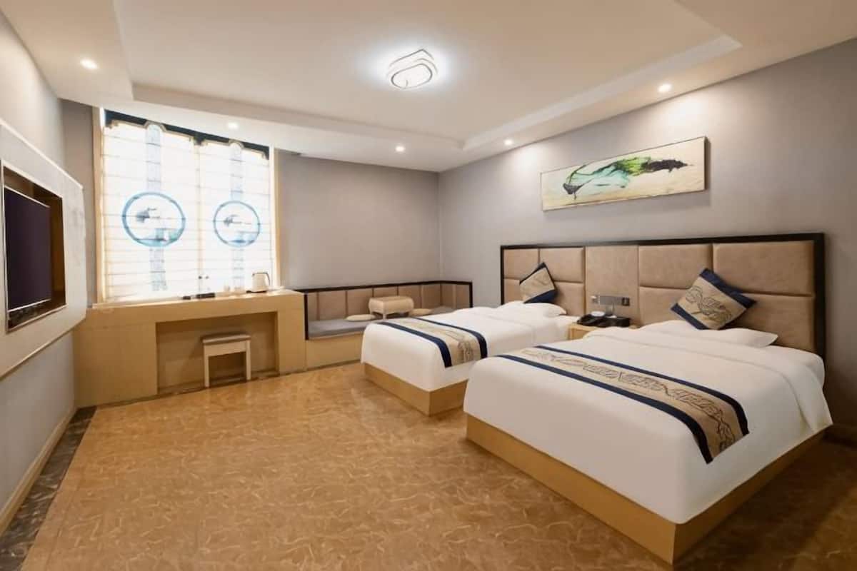 Una habitación de hotel con dos camas, un escritorio, una ventana con persianas y un cuadro en la pared.