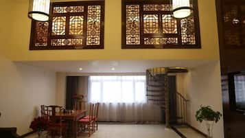 A spacious living area with a dining table, chairs, and a staircase leading to an upper floor.