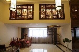 Amplia sala de estar con mesa de comedor, sillas y una escalera que lleva a un piso superior.