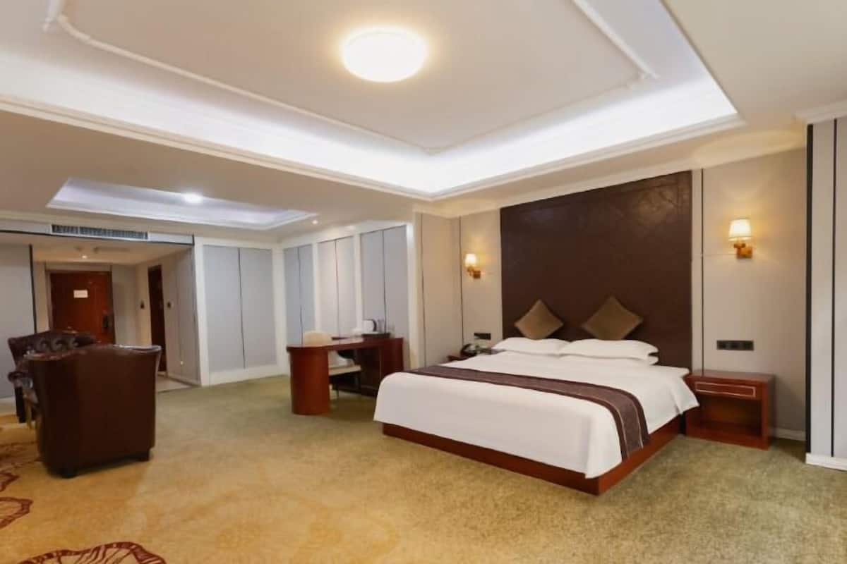Habitación de hotel con una cama grande, un escritorio, una silla y piso alfombrado.