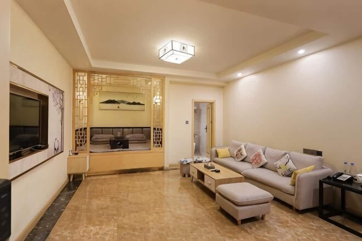 Una sala de estar con sofá, reposapiés, televisor y paneles decorativos en la pared.