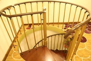 Una escalera en espiral con barandilla de madera y balaustrada de metal.