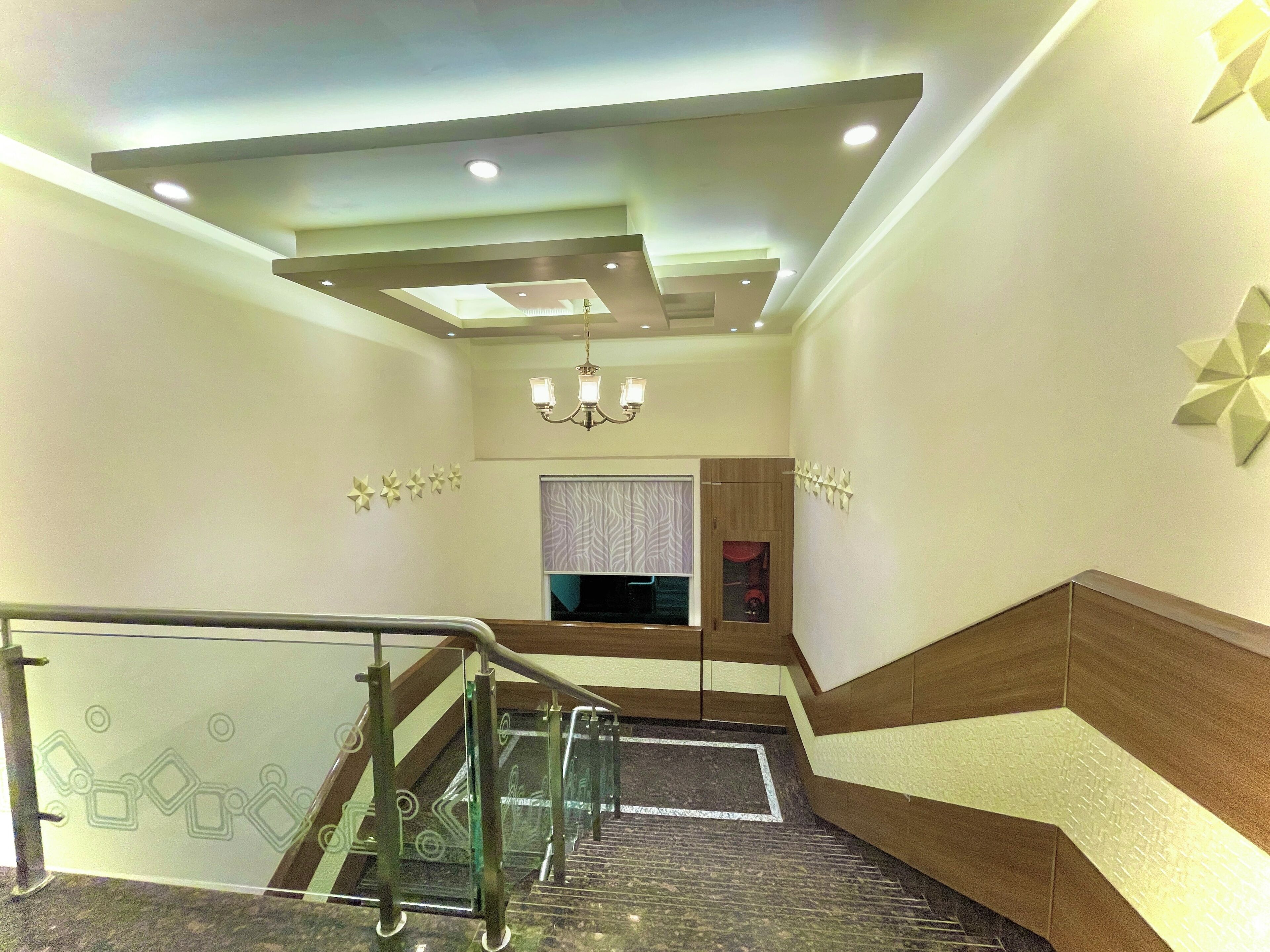 Um interior moderno com guarda-corpo de vidro, um candelabro e uma parede estampada.