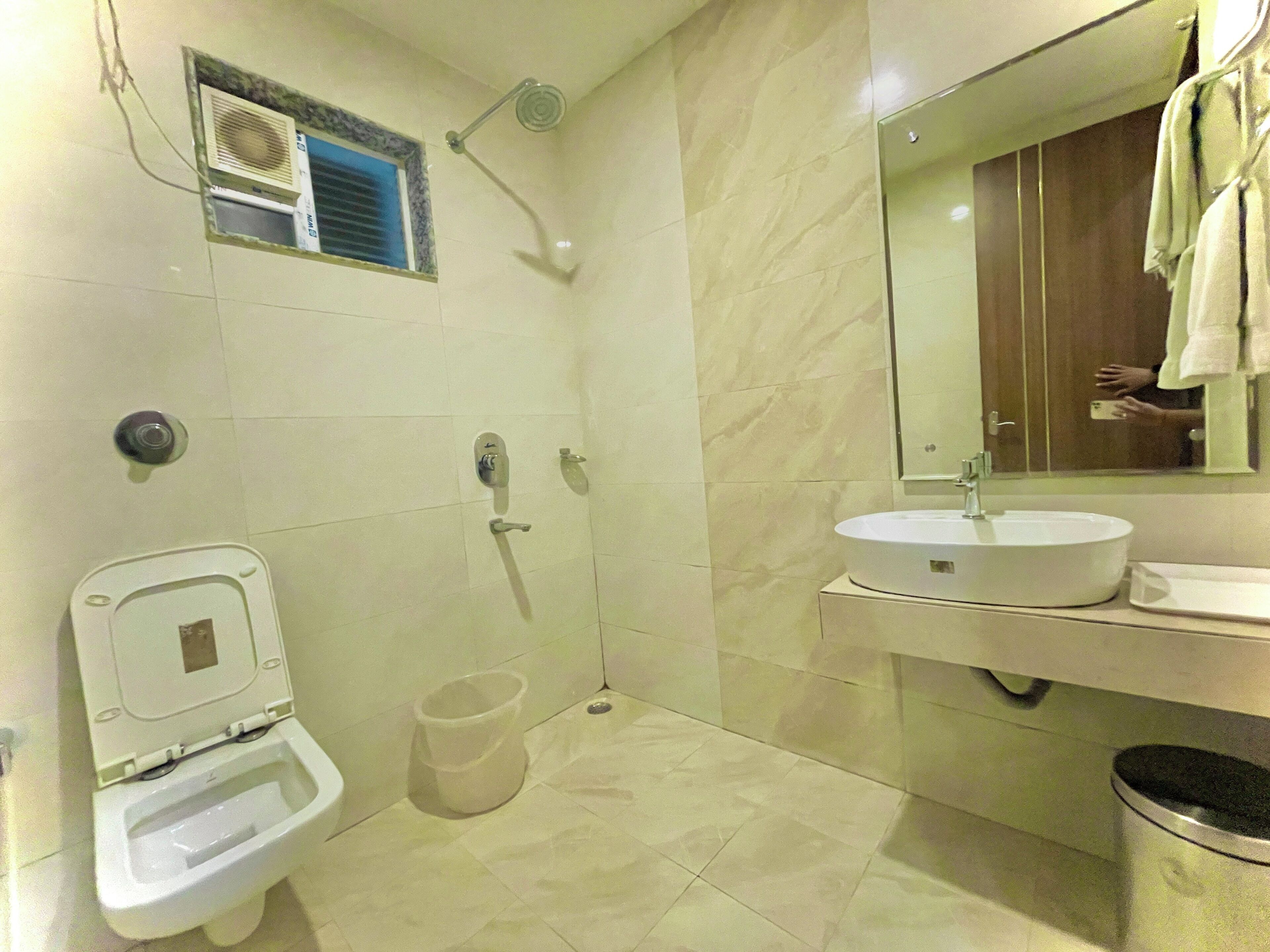 Une salle de bain comprenant des toilettes, un bidet, une douche, un lavabo et une poubelle.