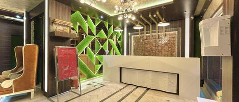 A hotel reception area with a modern design, including a reception desk, seating area, and decorative wall panels.