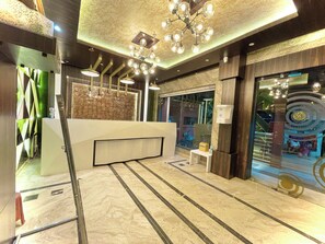 Un espace d’accueil doté d’un sol en marbre, d’un comptoir de réception et d’un lustre moderne.