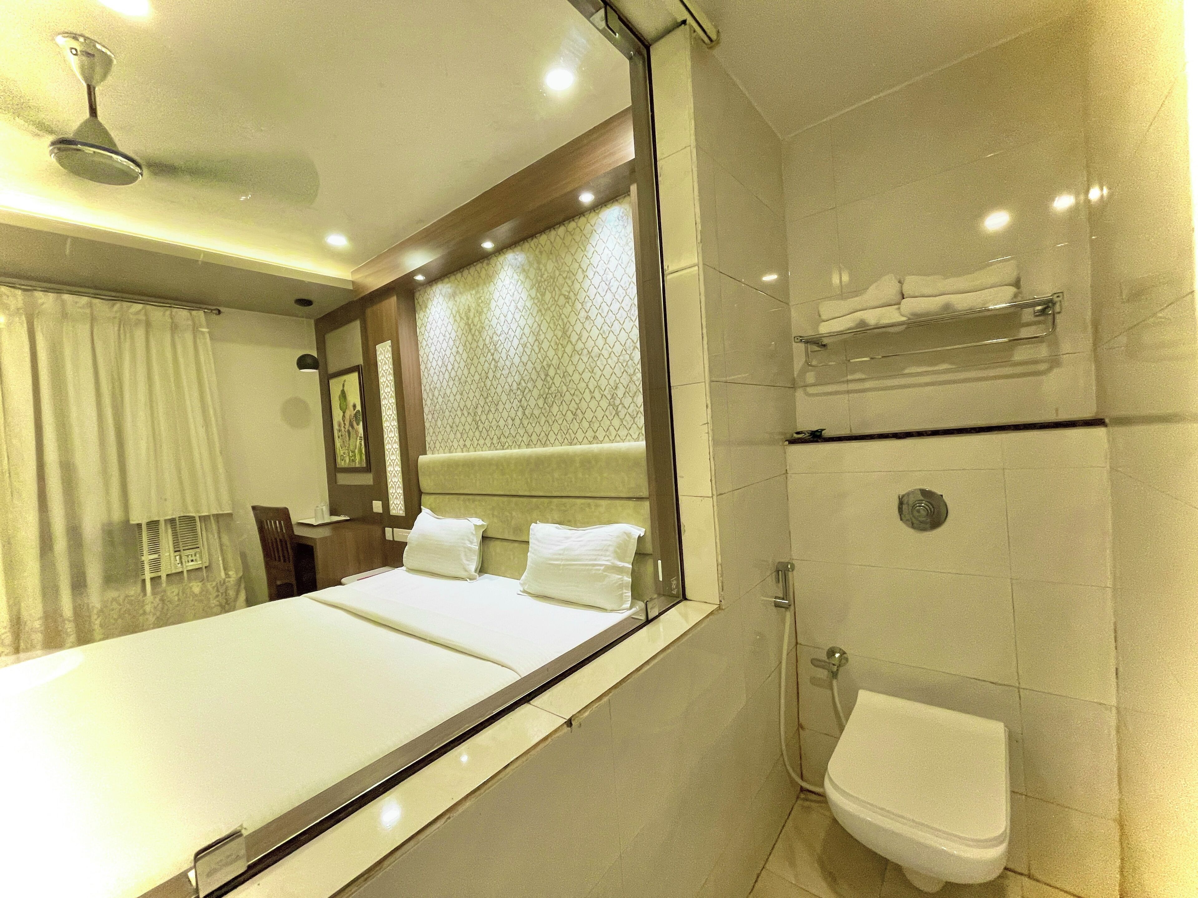 A hotel room with a large bed, a shower, and a toilet.