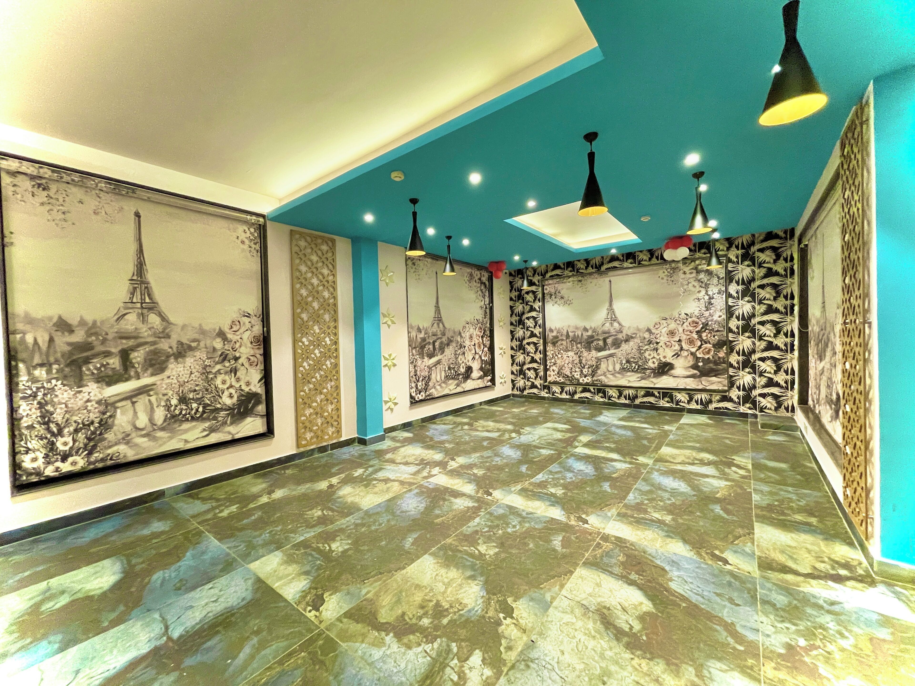 A spacious room with a tiled floor, large framed pictures of Paris, and modern pendant lighting.