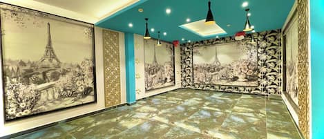 A spacious room with a tiled floor, large framed pictures of Paris, and modern pendant lighting.