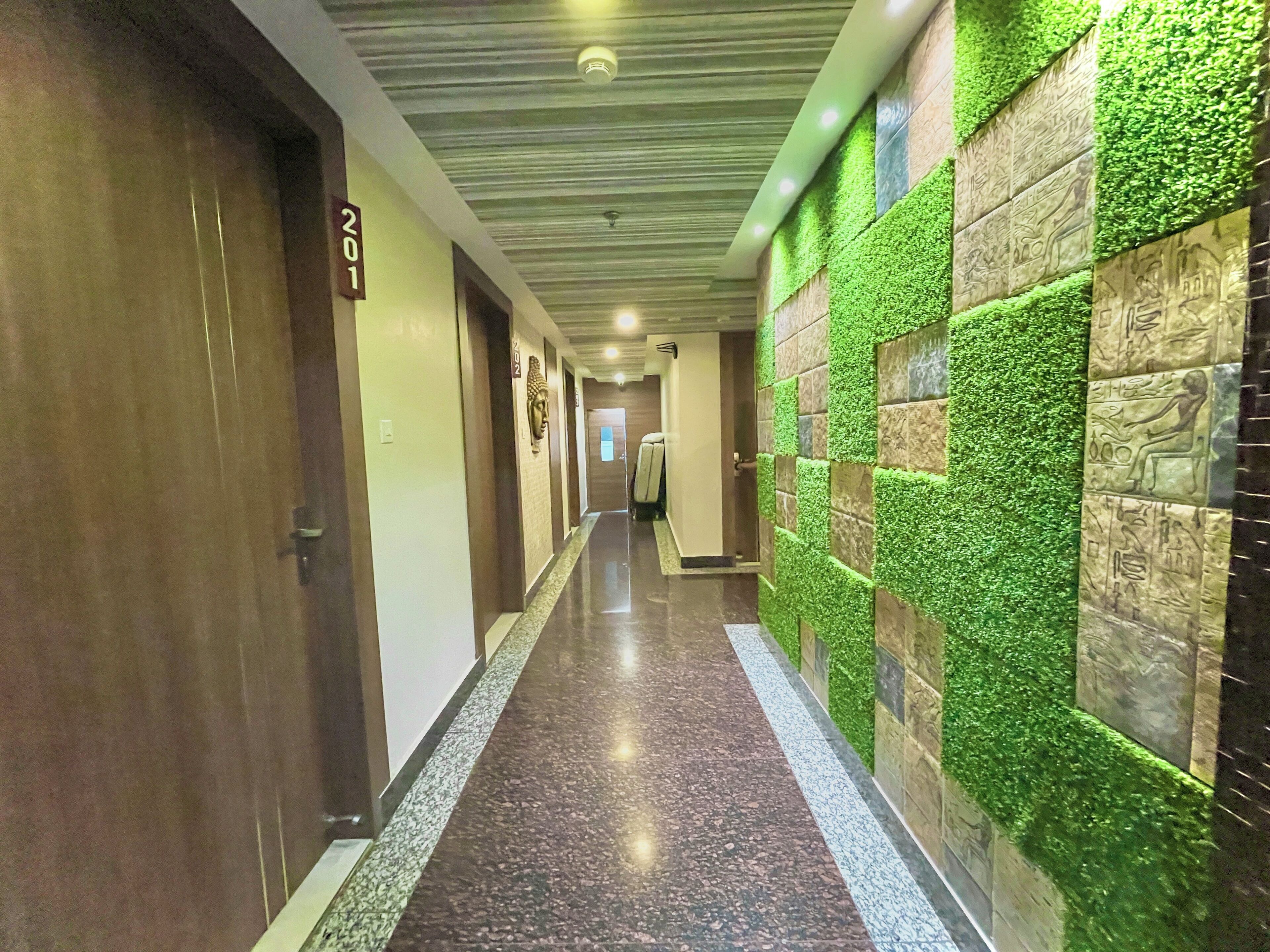 A hallway with a marble floor, green wall accents, and numbered doors.