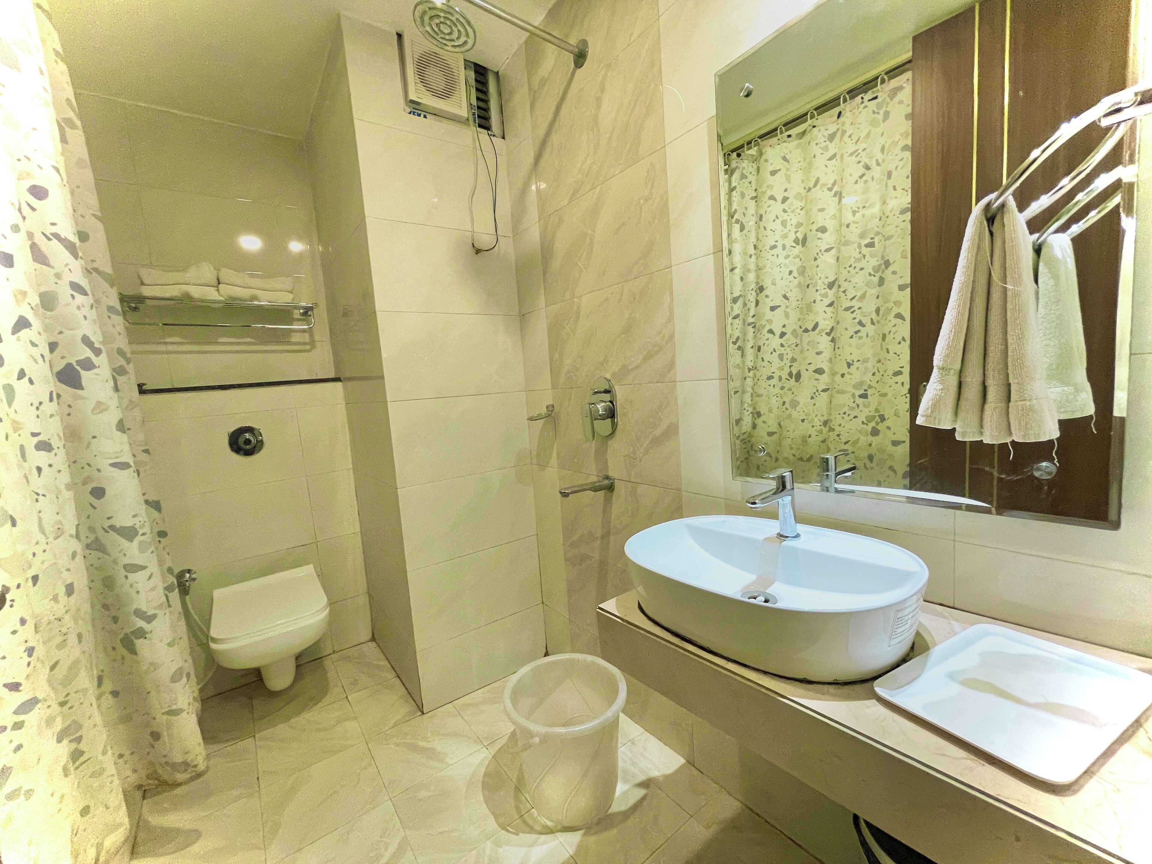 A bathroom with a shower, toilet, sink, and a towel rack.
