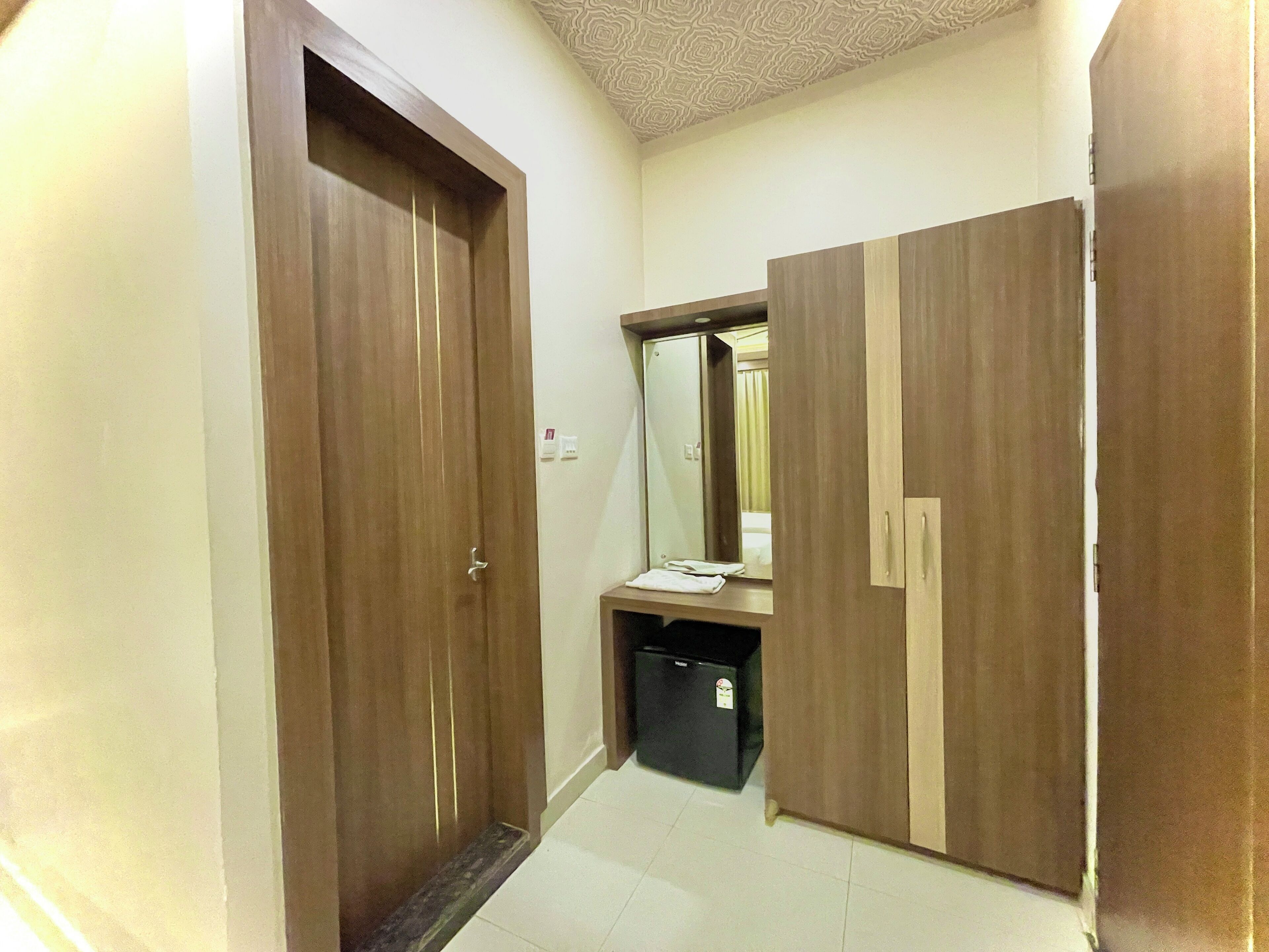 Un couloir avec des portes en bois, un miroir et une petite poubelle.