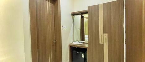 A hallway with wooden doors, a mirror, and a small trash bin.