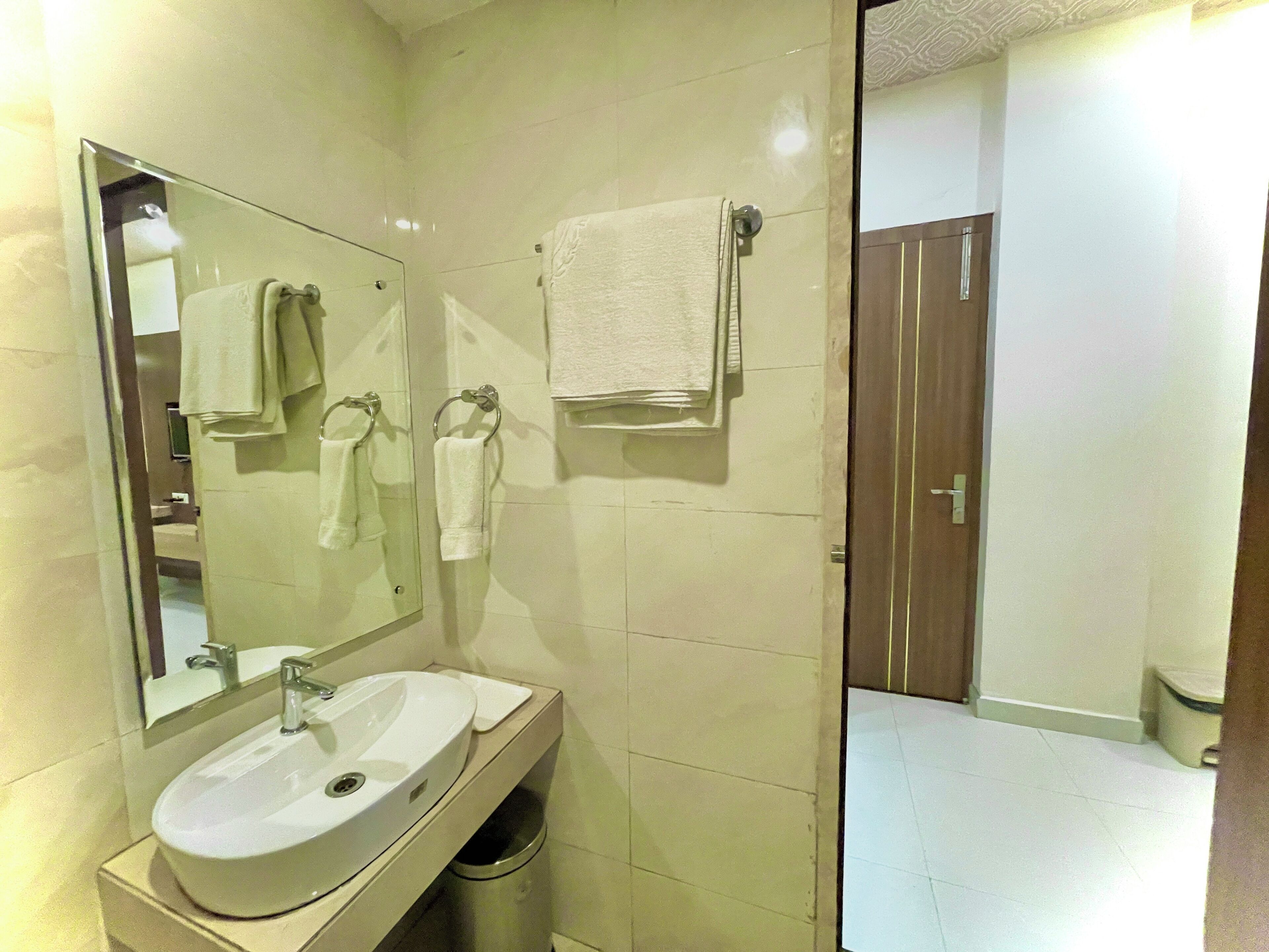 A bathroom with a sink, mirror, and two towels hanging on hooks.