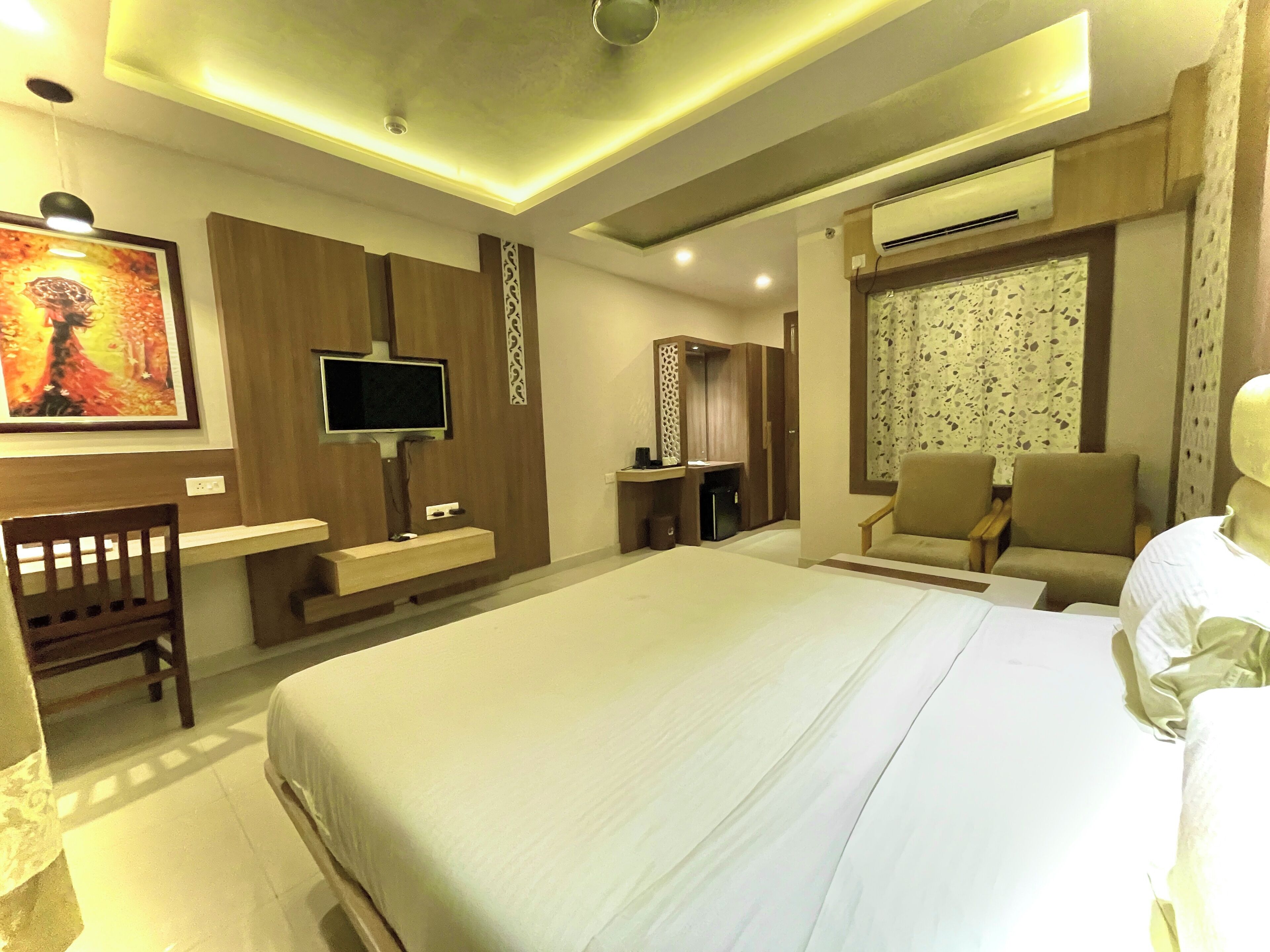 Habitación de hotel con una cama grande, televisión, escritorio y silla.