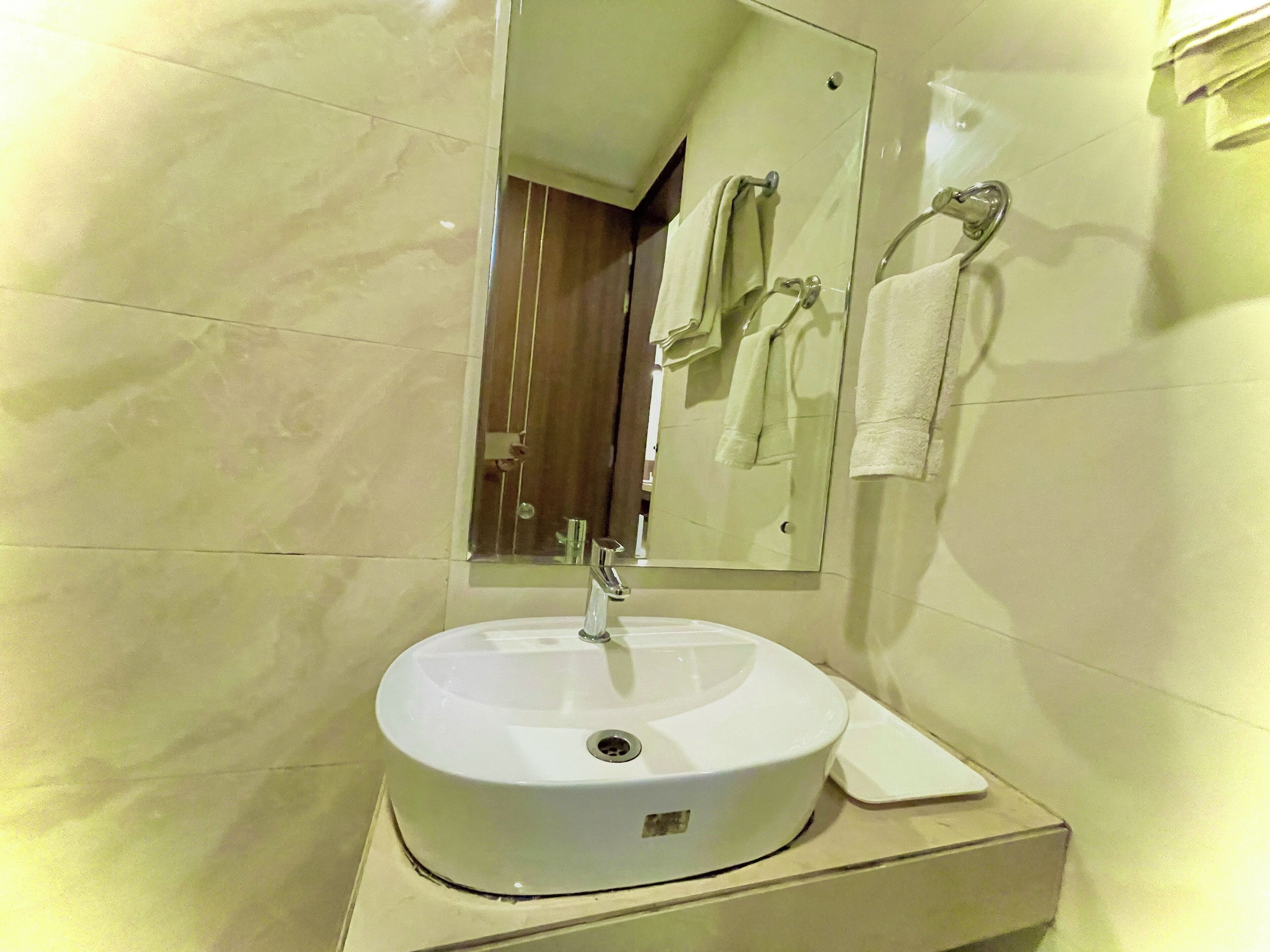A bathroom with a white sink, a mirror, and a towel rack.