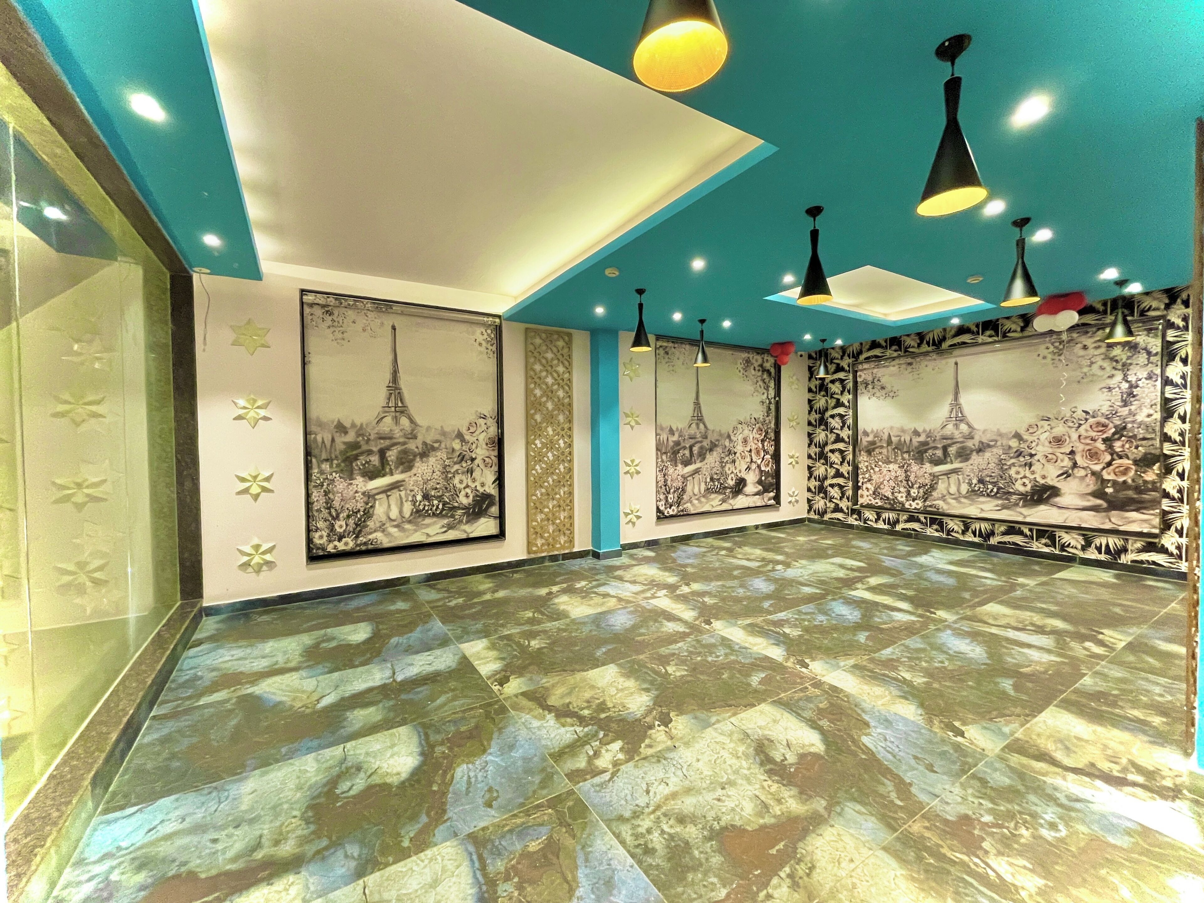 Una habitación amplia con un gran mural de la Torre Eiffel, piso estampado e iluminación colgante moderna.